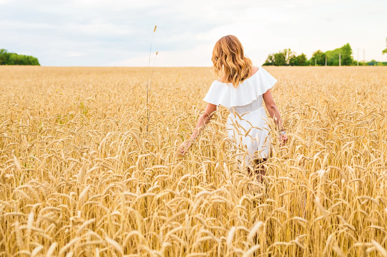 Mujer caminando por un campo de trigo dorado