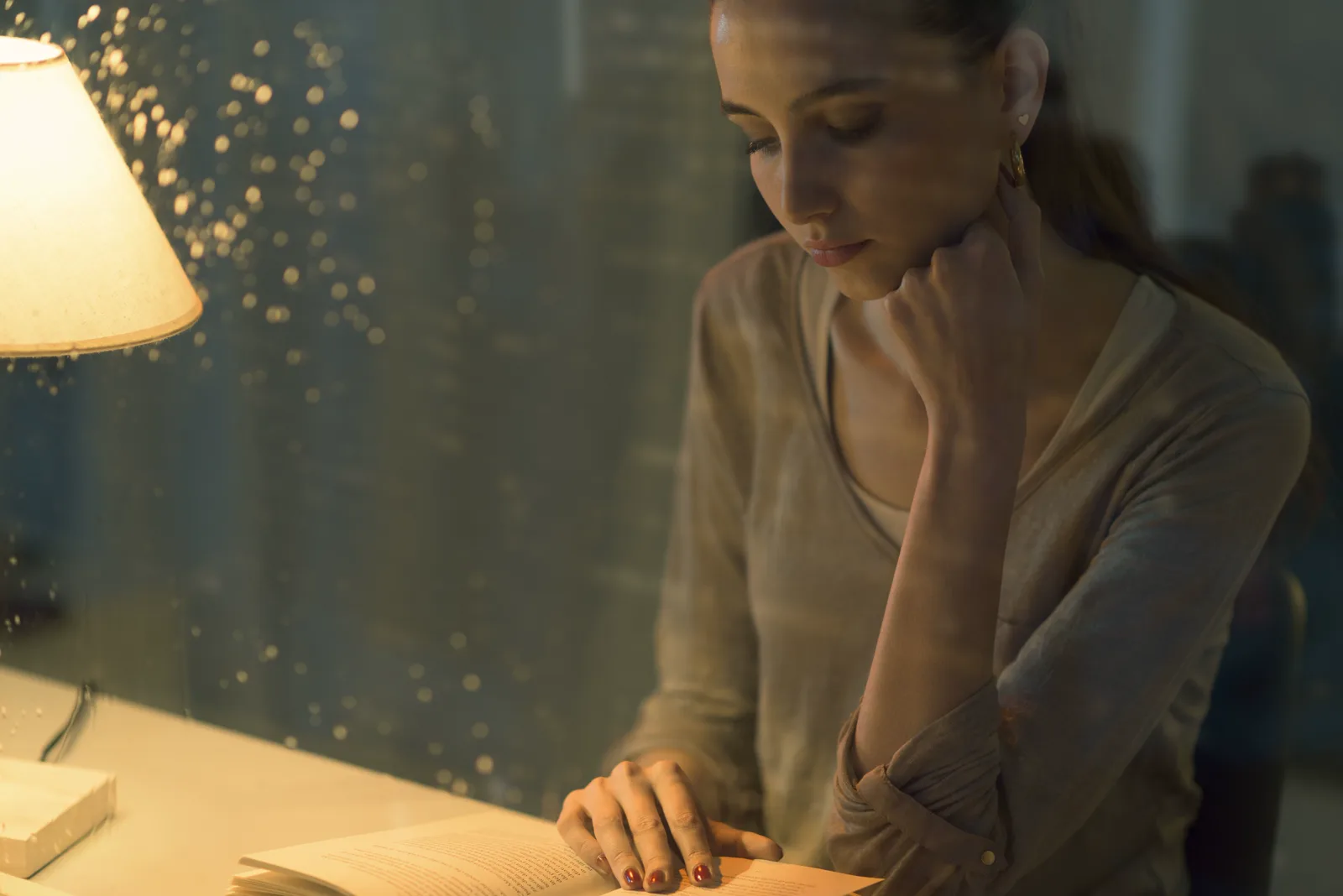 Mujer leyendo de noche junto a una lampara