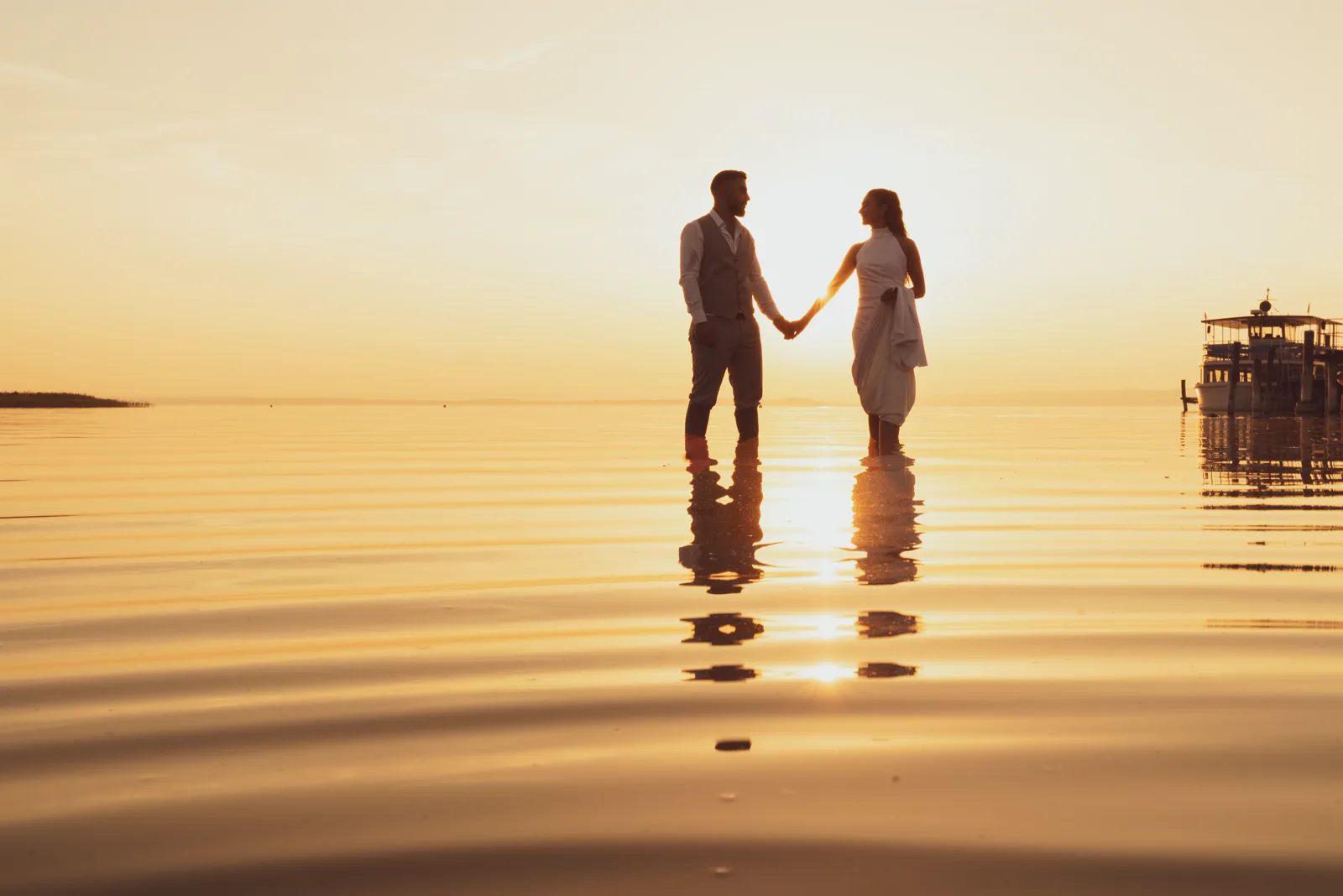 Pareja de la mano al atardecer sobre el agua